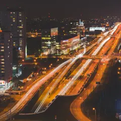 Tętniące życiem miasto nocą, z rozświetloną autostradą i wieżowcami.
