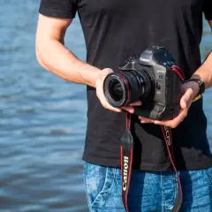 Mężczyzna trzyma aparat Canon EOS-1D Mark II z obiektywem, idealny do fotografii krajobrazowej dzięki matrycy APS-C.