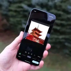 Dłoń trzyma smartfon z edytorem zdjęć. Na ekranie widać pagodę, a poniżej opcje edycji, w tym "Narzędzia", które pomogą Ci jak zmienić format zdjęcia.