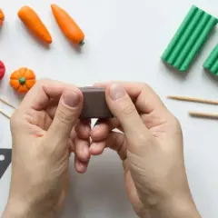 Ręce formują brązową masę, otoczone warzywami z plasteliny. Powstaje animacja poklatkowa z warzywnym ogródkiem.