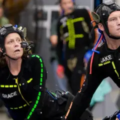 Aktorzy w strojach do motion capture, z markerami na twarzach i ciałach, przygotowują się do sceny.