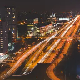 Tętniące życiem miasto nocą, z rozświetloną autostradą i wieżowcami.