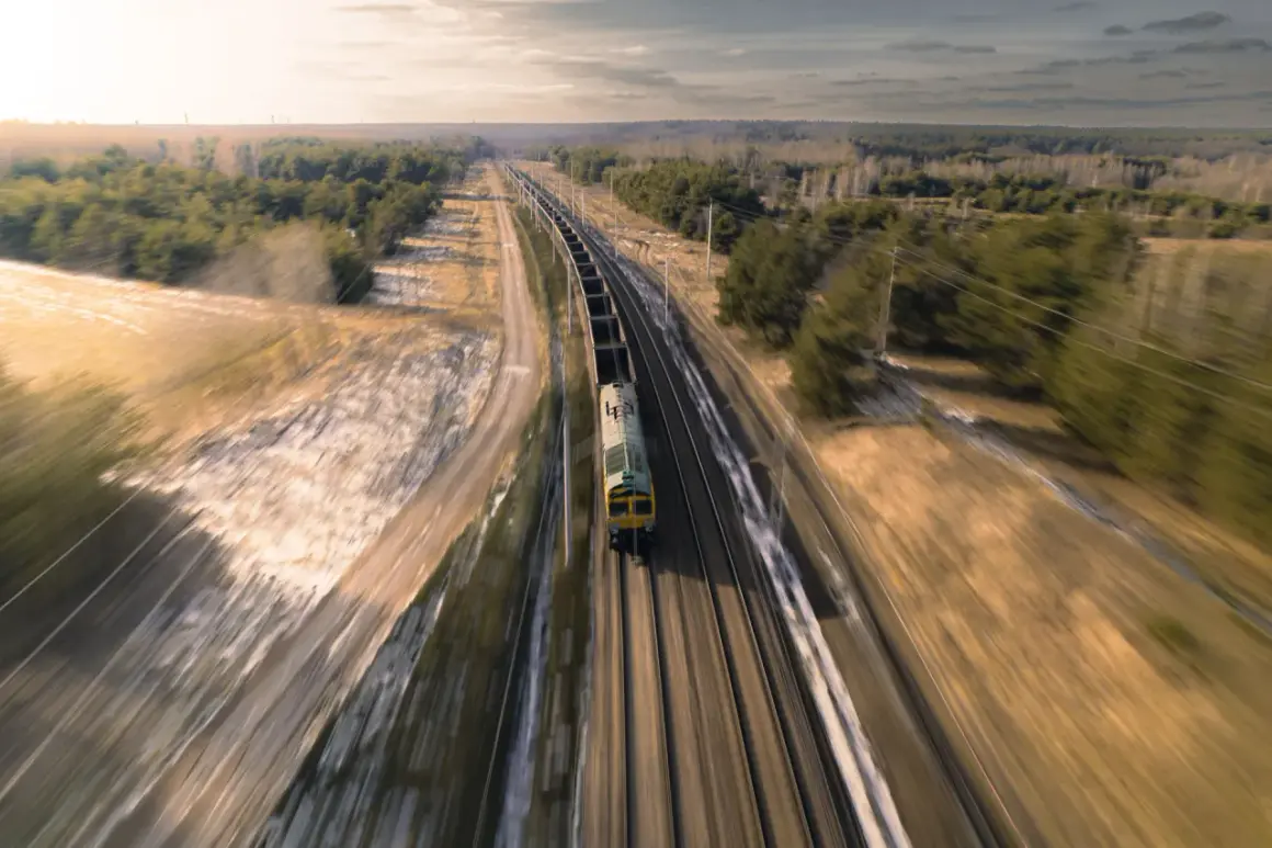 Pociąg towarowy pędzi po torach, krajobraz rozmyty przez efekt panning.