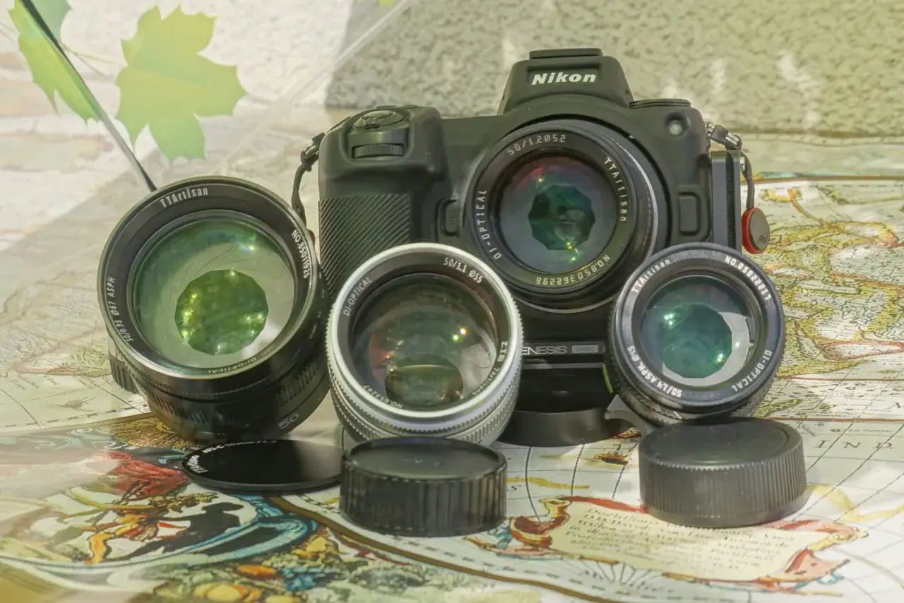 Aparat Nikon z trzema obiektywami TTArtisan i dekielkami na tle starej mapy.