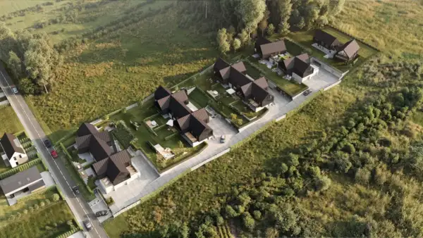 Nowoczesne domy z ciemnymi dachami i ogrodami, otoczone zielenią. Widok z lotu ptaka, jakby z **timelapse** pokazujący rozwój osiedla.