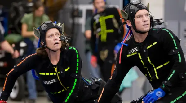 Aktorzy w strojach do motion capture, z markerami na twarzach i ciałach, przygotowują się do sceny.